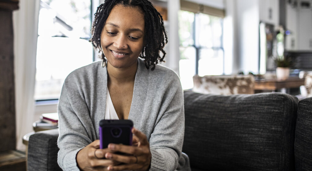 Woman holding smartphone on sofa at home